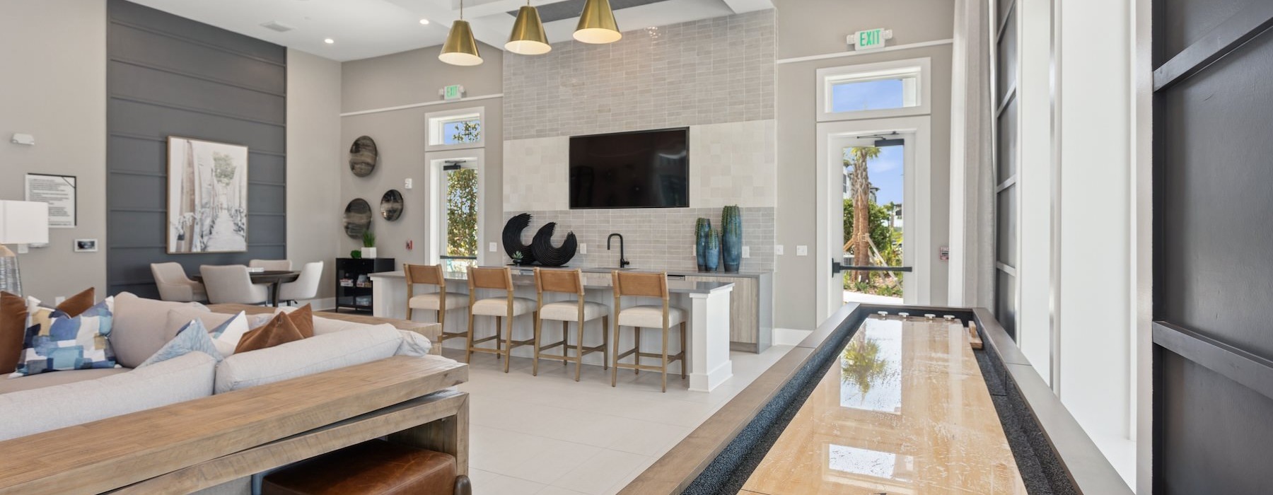a clubroom with a tv, shuffleboard table, chairs and tables